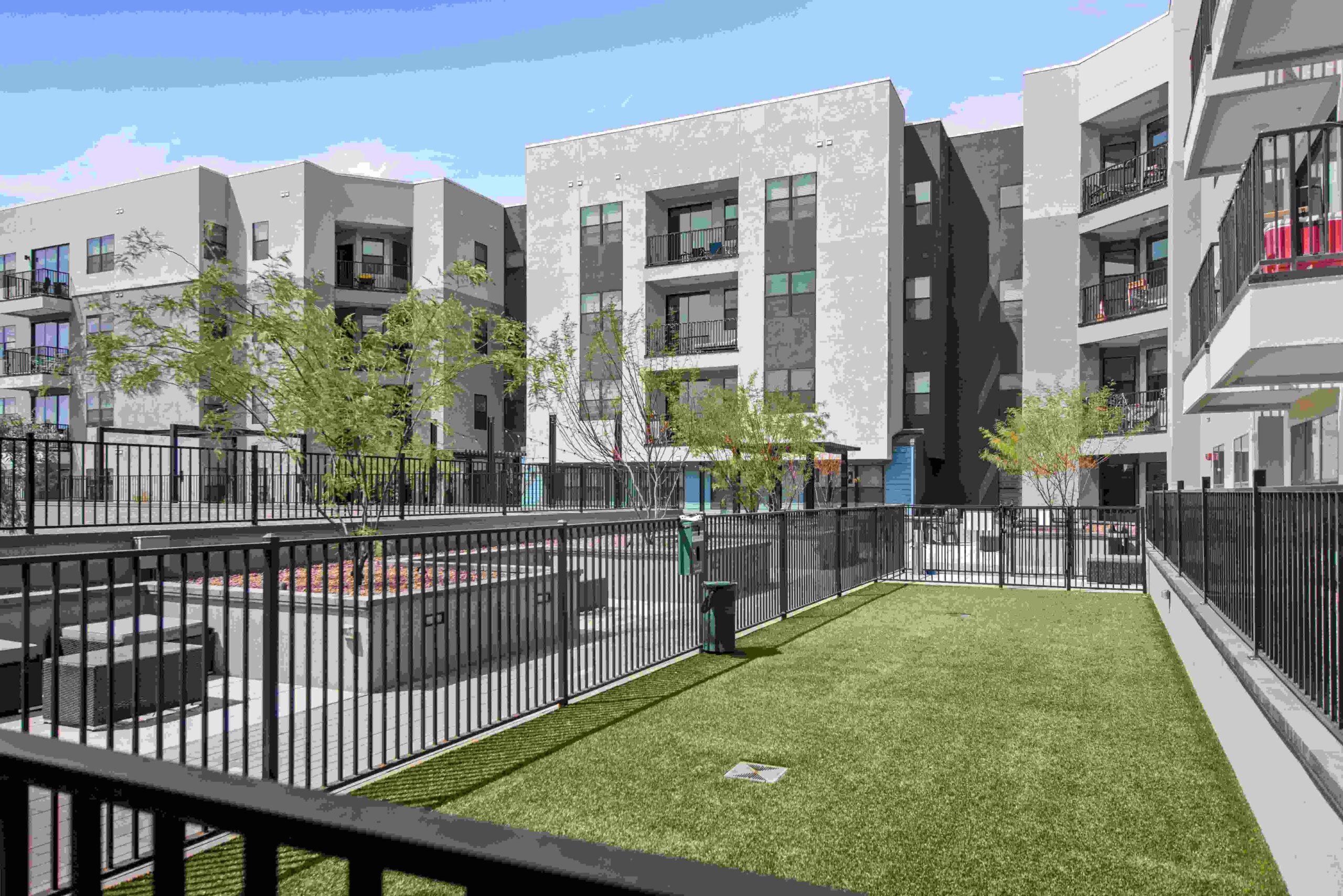 Apartment complex courtyard with green lawn and landscaped areas scaled