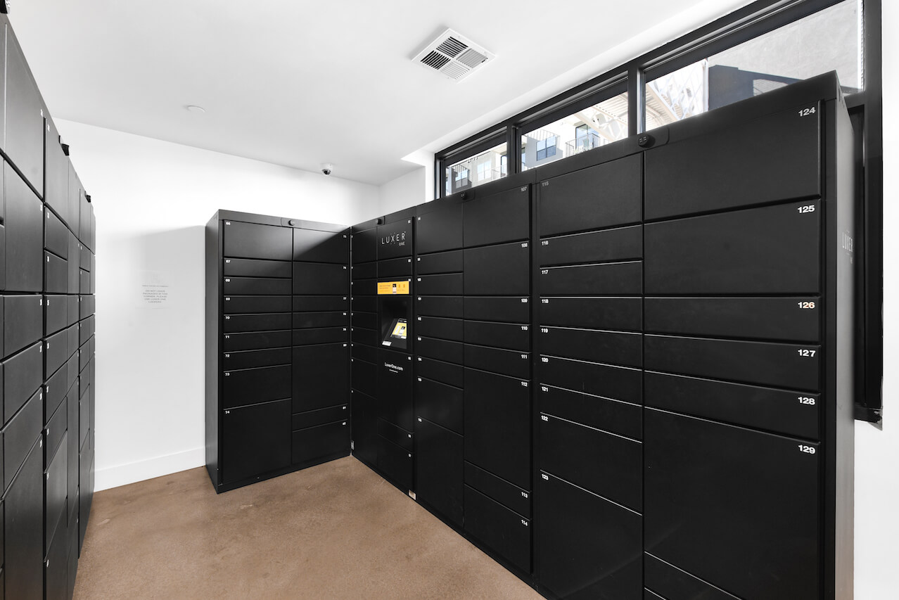 Black package lockers in a modern room with large windows