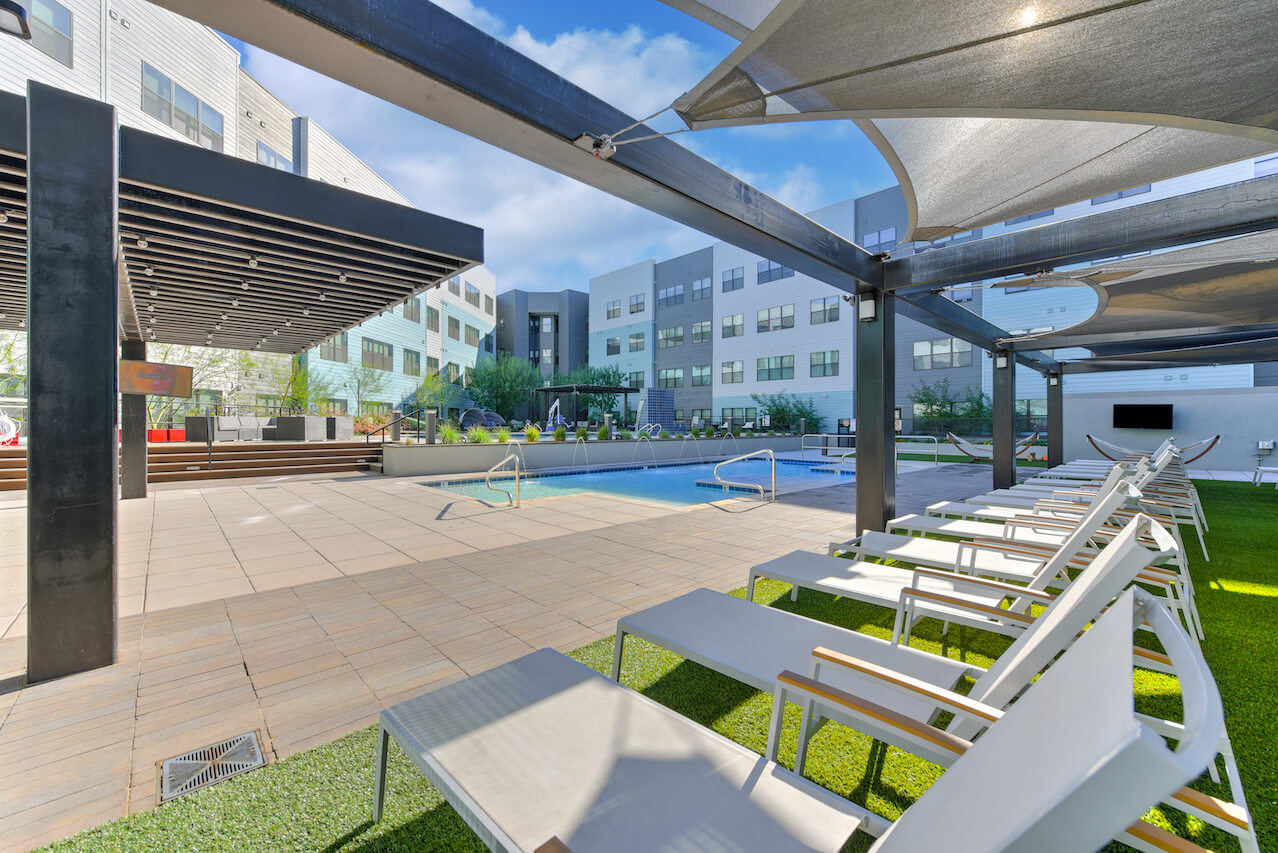 Lounge chairs by a pool in a sunny outdoor area