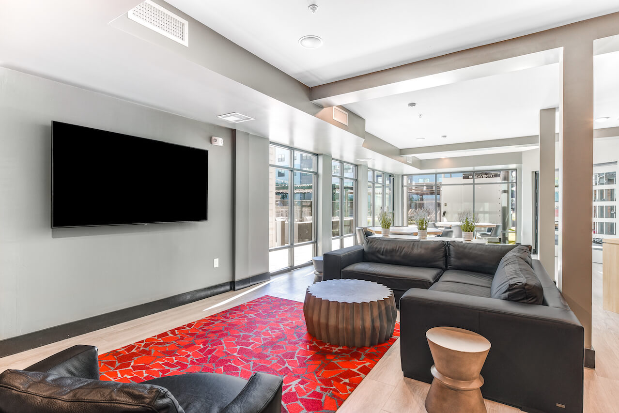 Modern lounge area with black couches a coffee table and a TV