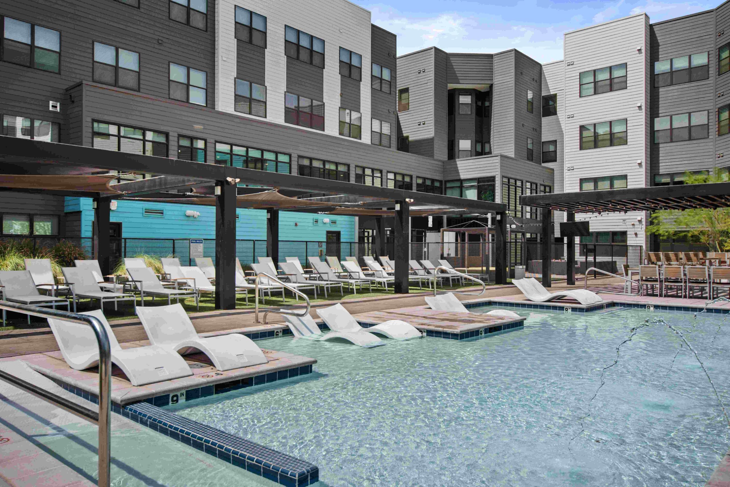 Modern pool area with lounge chairs and residential buildings scaled