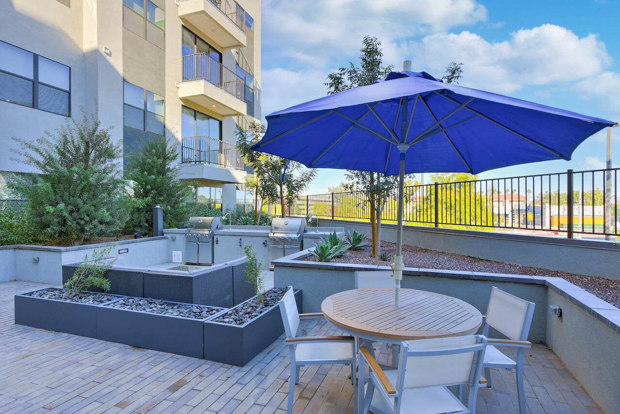 Outdoor lounge area with a round table chairs and barbecue grills