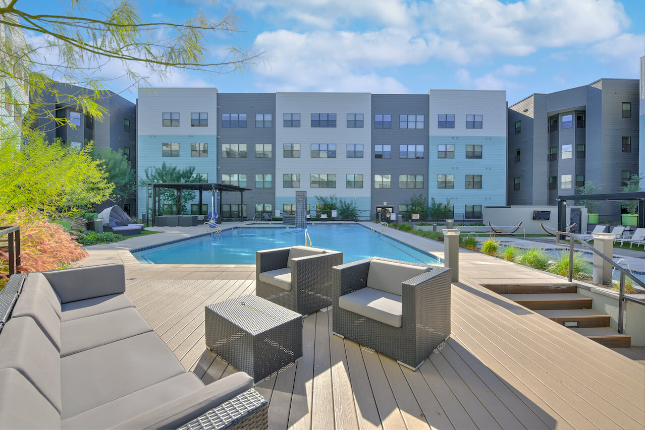 Poolside lounge area with chairs and modern apartments